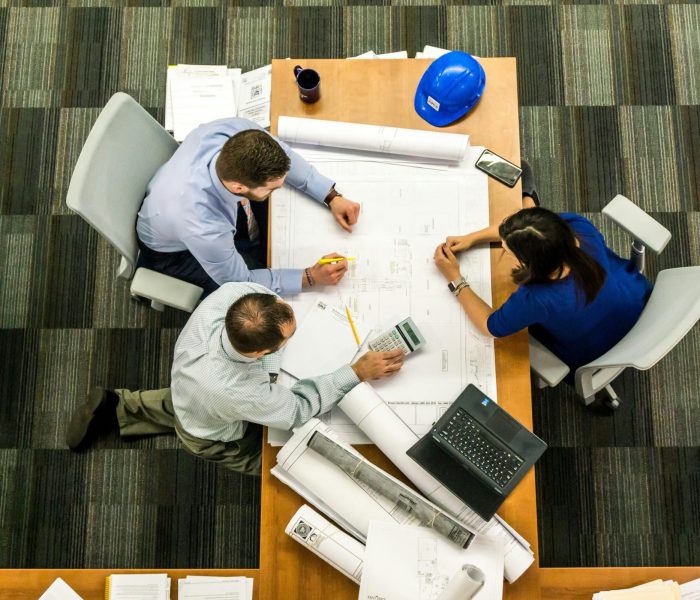 Top view of a team working on construction plans in an office setting.
