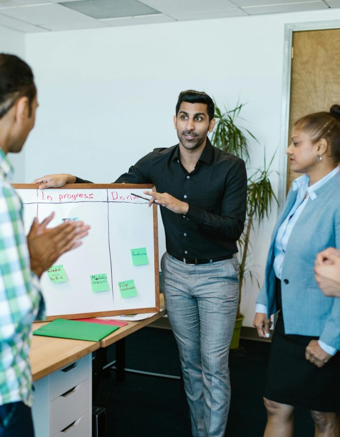 Diverse team discussing project progress with a board in a modern office.